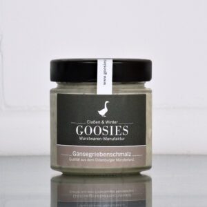 Gänsegriebenschmalz der Goosies Wurstwarenmanufaktur im 150-g-Glas, auf einem Edelstahltisch vor weißem Hintergrund