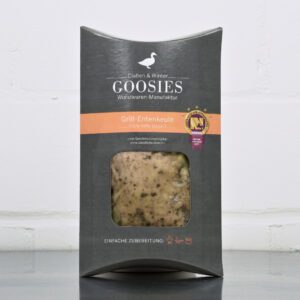 Sous-vide gegarte Grill-Entenkeule der Goosies Wurstwarenmanufaktur in einer 190-g-Packung auf einem Edelstahltisch vor weißem Hintergrund
