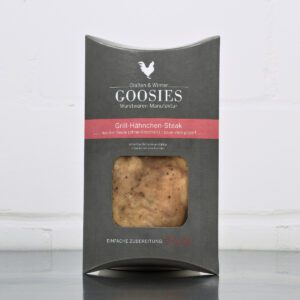 Sous-vide gegartes Grill-Hähnchensteak der Goosies Wurstwarenmanufaktur in einer 220-g-Packung auf einem Edelstahltisch vor weißem Hintergrund