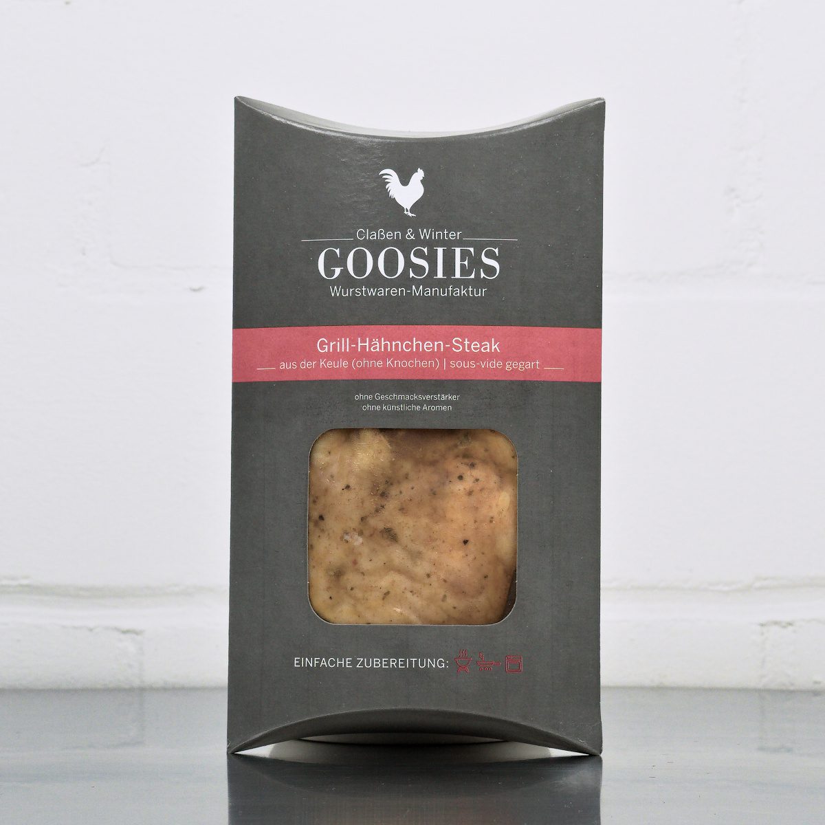 Sous-vide gegartes Grill-Hähnchensteak der Goosies Wurstwarenmanufaktur in einer 220-g-Packung auf einem Edelstahltisch vor weißem Hintergrund