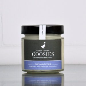 Reines Gänseschmalz der Goosies Wurstwarenmanufaktur im 150-g-Glas, auf einem Edelstahltisch vor weißem Hintergrund