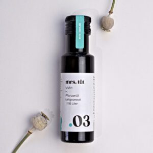 Kaltgepresstes Mohnöl von mrs. tüt Ölmanufaktur in 100-ml-Flasche, dekoriert mit Mohnpflanze vor einem weißem Hintergrund