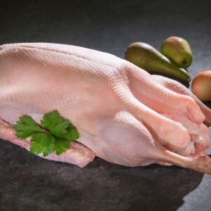 Rohe Weihnachtsgans vom Gänsehof Claßen, dekoriert mit Birnen und Petersilien auf grauem Untergrund