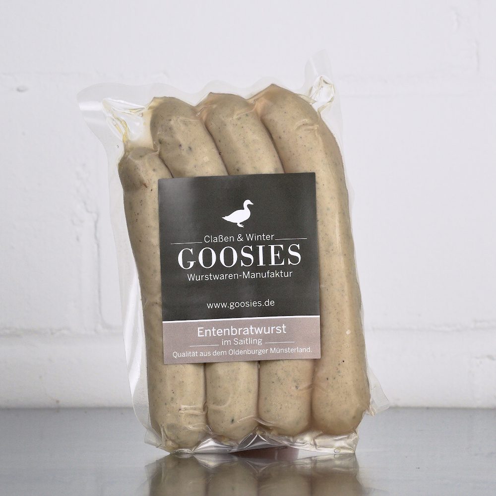 Entenbratwurst der Goosies Wurstwarenmanufaktur in einer 225-g-Packung mit vier Würstchen, auf einem Edelstahltisch vor weißem Hintergrund