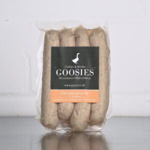 Gänsebratwurst der Goosies Wurstwarenmanufaktur in einer 225-g-Packung mit vier Würstchen, auf einem Edelstahltisch vor weißem Hintergrund