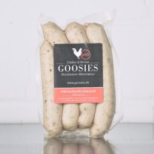 Hähnchenbratwurst BBQ der Goosies Wurstwarenmanufaktur in einer 225-g-Packung mit vier Würstchen, auf einem Edelstahltisch vor weißem Hintergrund