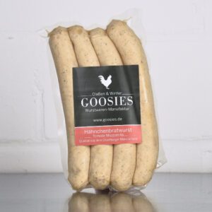 Hähnchenbratwurst Tomate-Mozzarella der Goosies Wurstwarenmanufaktur in einer 225-g-Packung mit vier Würstchen, auf einem Edelstahltisch vor weißem Hintergrund